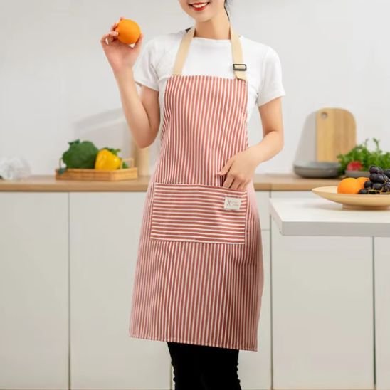 Femme souriante avec Tablier de cuisine tenant une orange dans la cuisine