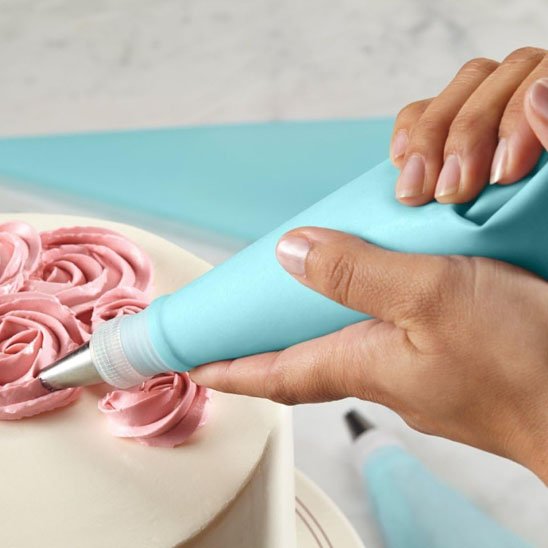 Décoration de gâteau avec poche à douille et crème rose