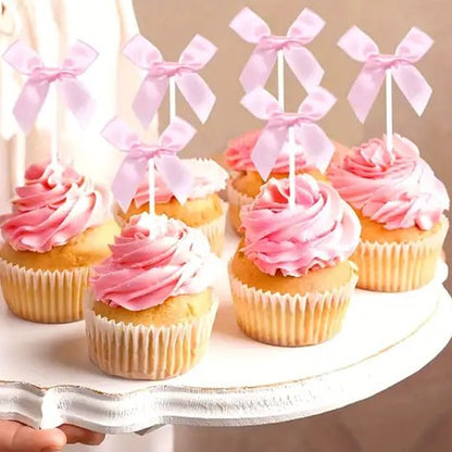 des cupcakes avec un glaçage rose tourbillonné chacun surmonté d'un ruban decoration gateau anniversairerose délicat