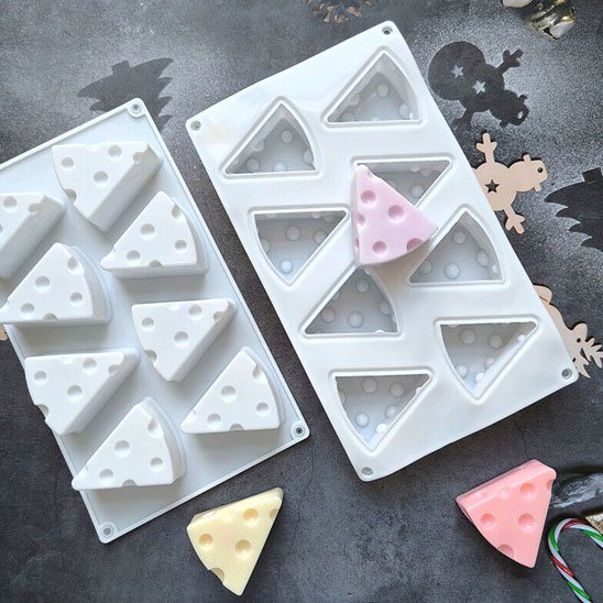 Des moules en silicone en forme de parts de fromage entourent des gâteaux colorées démoulées