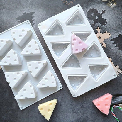 Des moules en silicone en forme de parts de fromage entourent des gâteaux colorées démoulées