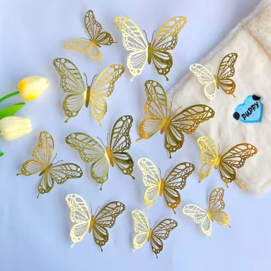 des papillons deco gateau dorés et blancs disposés sur une surface blanche avec quelques fleurs jaunes