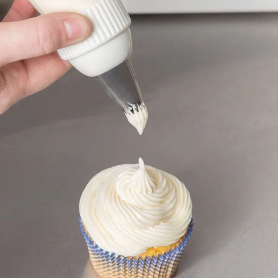 Douille patisserie appliquant crème blanche sur cupcake