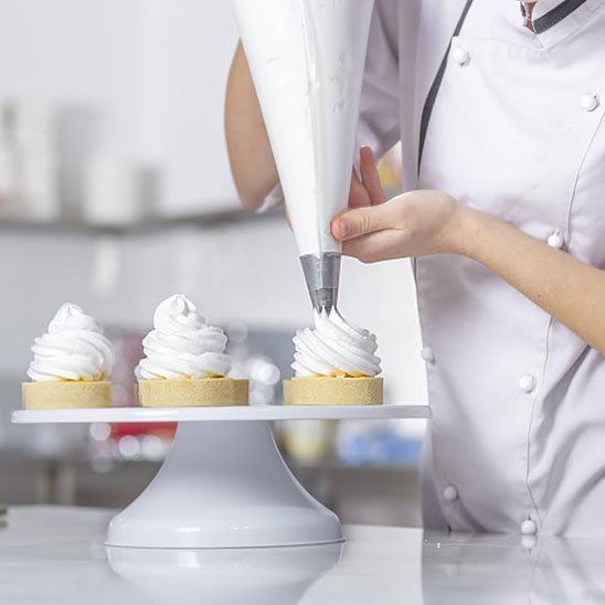 Douille patisserie décorant des tartelettes avec crème blanche