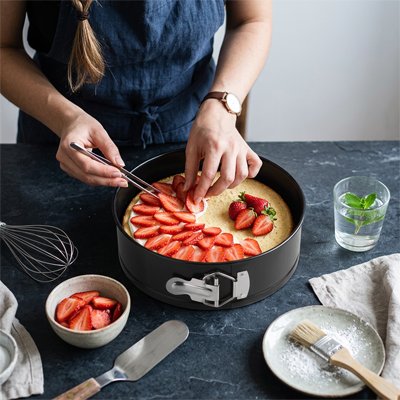 Femme décorant un gâteau avec des fraises dans Moule a manqué 