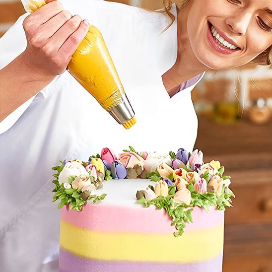 femme décore avec poche à douche un gâteau par une crème jaune