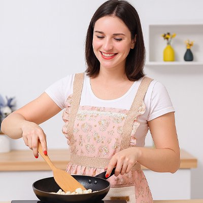 Femme en train de cuisiner portant un tablier de cuisine à fleurs roses