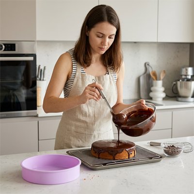 Femme versant du chocolat sur un gâteau cuit dans Moule a manqué
