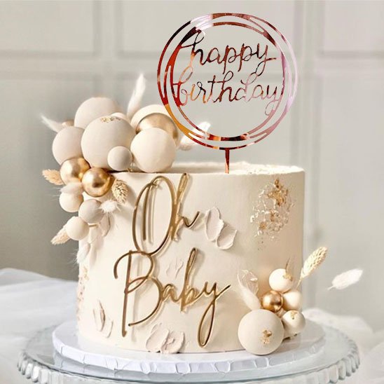 gâteau de fête décoré avec des ballons dorés, des éléments floraux et deco gateau  "Happy Birthday" au-dessus de l'inscription "Oh Baby"