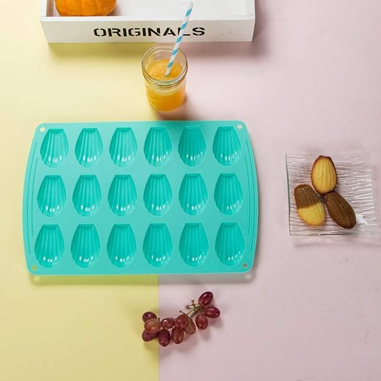 Moule à madeleine avec madeleines sur assiette et fruits