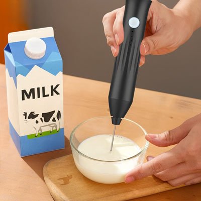 Mousseur à lait noir fouettant du lait dans un bol