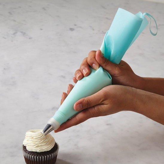 Poche à douille décorant un cupcake avec crème blanche