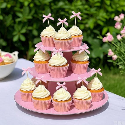 présentoir à trois niveaux montrant des cupcakes avec decoration gateau anniversaire de rubans roses, disposés de manière élégante