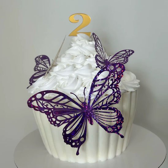 un gâteau décoré de crème blanche avec un deco gateau topper en forme des papillons violets