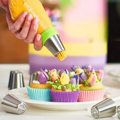 Une personne décore des cupcakes colorés avec une poche à douille remplie de crème jaune